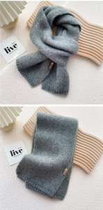 Detail of grey knitted scarf with soft mohair texture and premium leather logo tag