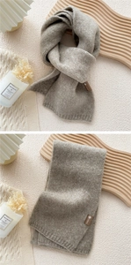Close-up of soft knitted scarf in light oatmeal color with ribbed edges and minimal logo