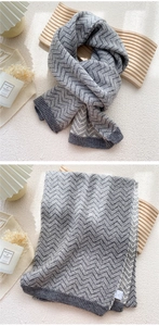 Detailed close-up of thick grey and beige herringbone knit scarf with ribbed edge details