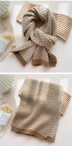 Detail of soft knit scarf featuring a classic herringbone pattern and ribbed edges