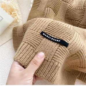 Détail d'une écharpe en maille marron clair avec tissage damier et étiquette noire
