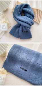 Détail de l'écharpe en maille bleue à damier avec étiquette tissée et texture d'hiver