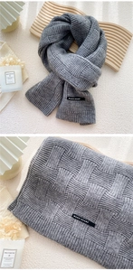 Détail d'une écharpe en tricot gris avec motif tressé et étiquette de marque tissée