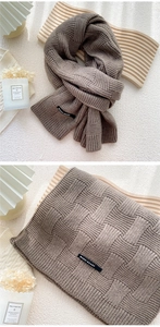 Détail d'une écharpe en maille épaisse avec tissage gaufré et étiquette sur plateau