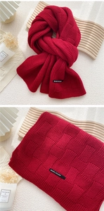 Vue macro d'une écharpe en maille bordeaux montrant la texture et l'étiquette tissée