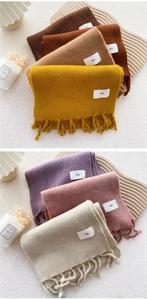 Detail von weichen Strickschals mit Fransen und minimalistischen Egg-Markenlabels
