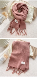 Detail eines rosa Strickschals mit Fransen und weißem Egg-Label auf weichem Stoff