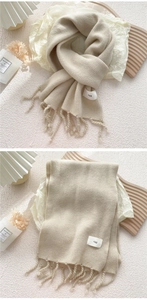 Detailansicht eines beigen Strickschals mit handgefertigten Fransen und Stoffetikett