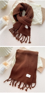 Detail eines dunkelbraunen Strickschals mit weicher Textur, Fransen und Egg-Label