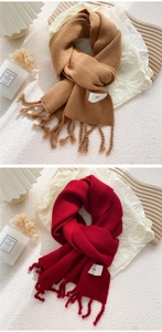 Detailaufnahme der weichen Strickschals mit Fransen in Camel und Rot auf hellem Grund
