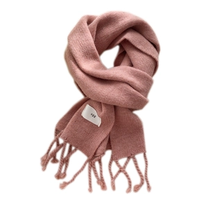 Weicher rosa Strickschal mit Fransen und kleinem Etikett auf weißem Hintergrund