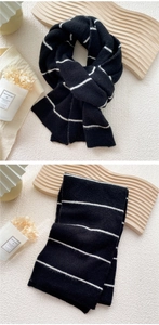 Detail of black and white striped knit scarf folded on a wooden tray for winter styling