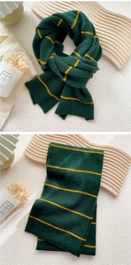 Detail of dark green and yellow striped knit scarf folded on a cream textured background