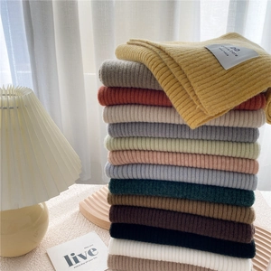 Multiple colorful knitted scarves stacked vertically with handmade labels for winter warmth
