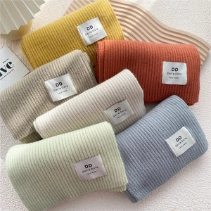 Detail of soft knit scarves in various colors with handmade label and ribbed texture