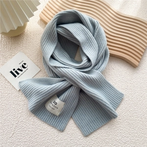Detail of light blue ribbed knit scarf featuring a white woven handmade brand label
