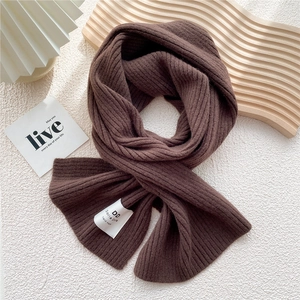 Close-up of thick dark brown knit scarf with vertical ribbed texture and hand-made label