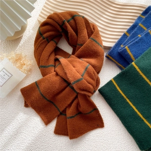 Three assorted striped knitted scarves in warm winter colors shown on a textured wooden tray