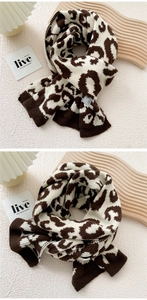 Detail of thick leopard print knit scarf with ribbed edges on a warm aesthetic background