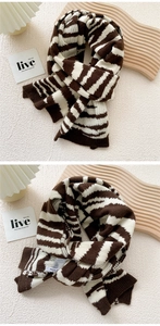 Detail of thick striped knit scarf in coffee and cream with ribbed edge texture