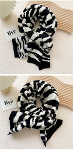 Detail of thick black and white striped knit scarf on a textured minimalist background