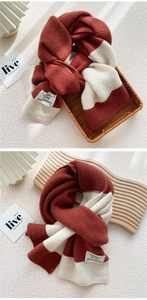 Detail of thick two-tone knit scarf featuring a rustic red and cream patchwork texture