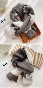 Close-up of thick knit striped scarf showing grey and beige textures with brand label