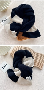 Detail of black and white striped knit scarf with decorative woven label and thick texture