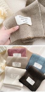 Detail of soft herringbone knit scarf with woven labels and multiple color options