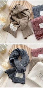 Detail of herringbone knit texture on thick winter scarves with decorative brand patches
