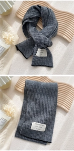 Close-up of black and grey herringbone knitted scarf with a white decorative patch