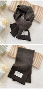 Detail of herringbone knit scarf with woven logo patch on thick warm winter material
