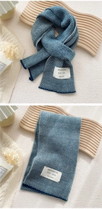 Detail of blue herringbone knit scarf with woven label on a wooden background