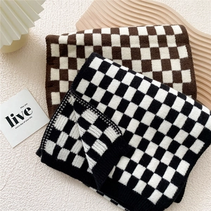 Thick checkered knitted winter scarf in black and coffee brown on wooden tray
