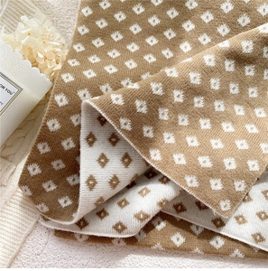 Close-up of double-sided jacquard knit scarf with geometric diamond pattern in camel and white