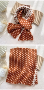 Detail of soft knitted scarf featuring orange and white geometric diamond pattern