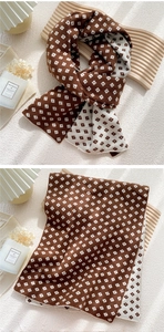 Detail of soft double-sided knit scarf featuring vintage plaid patterns in brown and beige