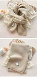 Macro detail of beige chunky knit scarf showing soft texture and woven brand label