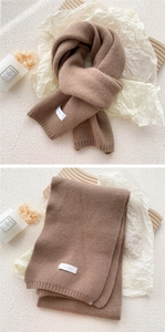 Detailed texture of brown knitted scarf with FEIDING brand label and ribbed hem detail