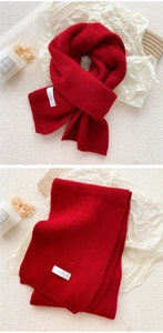 Close-up of red knitted scarf texture and minimalist brand label on winter fabric