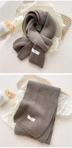 Detail of brown knitted scarf featuring thick plush texture and FEIDING woven brand label