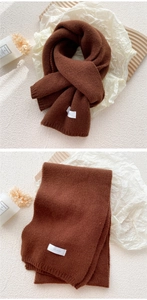 Detailed knit texture of thick dark brown winter scarf with stylish brand label