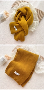 Close-up of mustard yellow ribbed knit scarf with soft wool texture and minimalist brand label