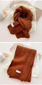 Close-up of caramel knit scarf featuring ribbed texture and stylish brand label
