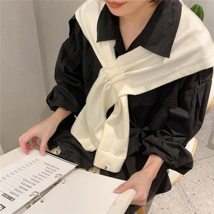 Cream knit shawl with K-letter label over a black button-down shirt for a layered look
