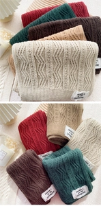 Close-up of thick knitted scarves with braided twist patterns and woven labels