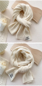 Detailed view of cream-colored chunky knit scarf with hollow texture and fashion label