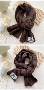 Detail of dark brown cable-knit scarf with thick texture and white fashion woven label