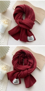 Detail of burgundy thick cable knit scarf texture and premium white fabric brand tag
