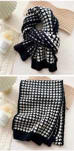 Detail of heart pattern knit scarf featuring black and white contrast and ribbed edges